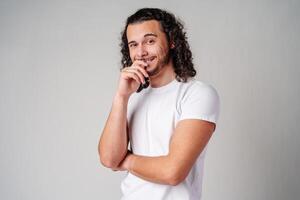 A young man stands thoughtfully against a plain background, expressing contemplation photo