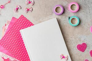 Creative supplies for scrapbooking and crafting on a textured surface with decorative tape and heart confetti photo