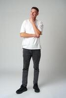 Full length portrait of young smiling man wearing casual clothes on gray background photo