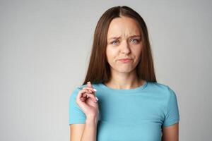Portrait of thoughtful uncertain young casual girl on gray background photo
