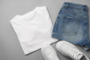 T-shirt, jeans and white sneakers on gray background top view photo