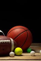 Set of various sport balls on wooden floor on black background photo