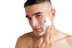 Young handsome man applying shaving foam against white background photo