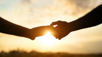 Two hands reaching for each other during sunset, symbolizing connection and intimacy in a serene outdoor setting photo