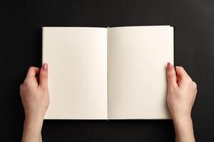 Open notepad in hands on black background photo