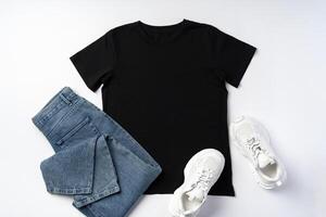 T-shirt, jeans and white sneakers on gray background top view photo