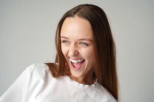 Cheerful young woman looking at camera smiling laughing over gray background photo