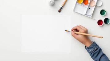 A person prepares to paint on a blank canvas with watercolor paints and brushes at a clean, organized workspace photo