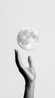 A hand reaches towards a glowing moon in a minimalist setting, capturing the essence of dreams and aspirations in black and white photo