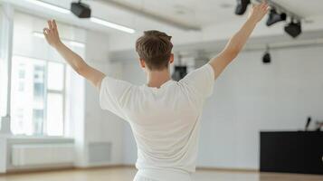Dancer practicing in a bright studio with arms raised during a rehearsal in the afternoon light photo