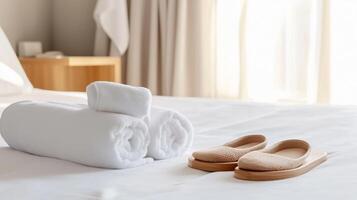 Soft towels and cozy slippers arranged neatly on a hotel bed in a bright, comfortable room during the day photo