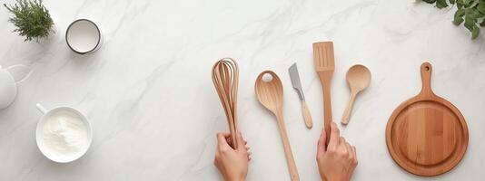 Kitchen utensils arranged on a countertop with hands preparing for cooking, showcasing various tools and a bowl of cream photo