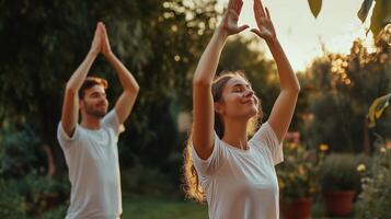 Couple practicing yoga outdoors during sunset in a serene garden surrounded by lush greenery and blooming flowers photo