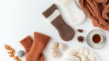 Cozy hand-knitted socks arranged with a warm drink and autumn leaves on a light surface for a homely atmosphere photo