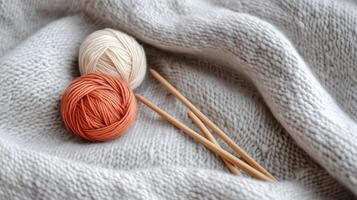 Yarn balls and knitting needles rest on a soft knit blanket, inviting creative crafting during a cozy afternoon photo