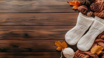 Cozy knitted socks on a wooden table surrounded by autumn leaves and yarn in a warm, inviting setting photo