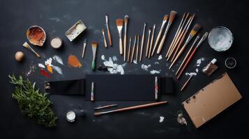 Art supplies neatly arranged on a dark tabletop featuring brushes, paints, and natural elements for creative projects photo