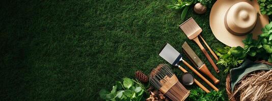 Gardening tools and accessories arranged on a lush green grass surface with natural elements and a sun hat nearby photo