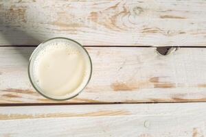 Glass of milk on table on blurred natural background photo