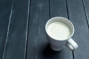 Glass of milk on table on blurred natural background photo