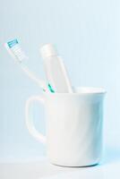 Toothbrushes in glass on table on light background photo