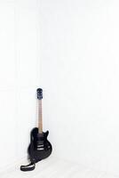 guitar propped in front of a white wall photo