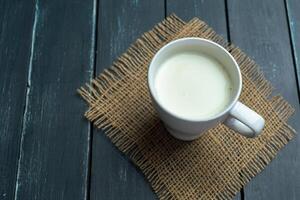 Glass of milk on table on blurred natural background photo