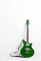 guitar propped in front of a white wall photo