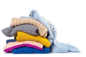 Stack of various sweaters isolated on white background photo