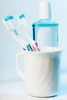 Toothbrushes in glass on table on light background photo
