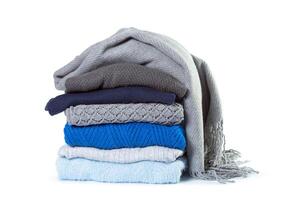Stack of various sweaters isolated on white background photo