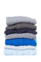 Stack of various sweaters isolated on white background photo