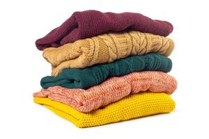 Stack of various sweaters isolated on white background photo