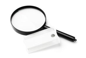 A magnifying glass and lice comb placed side by side on a clean white background photo