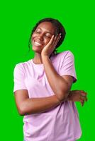 Happy young person laughing and playfully covering face while standing against a bright green background photo