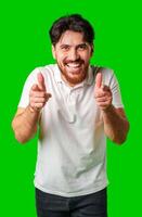 Smiling man gestures playfully with finger guns against a vibrant green background photo