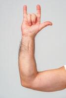 A person makes a hand gesture with the pinky and index finger raised against a plain background photo