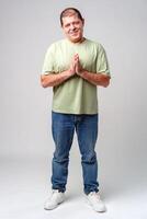 Smiling man standing with hands together in a gesture of greeting or thanks photo