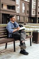 A person writes in a notebook while sitting on a park bench photo