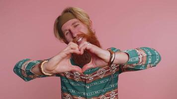 Smiling redhead man makes heart gesture demonstrates love sign expresses good feelings and sympathy video