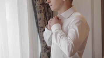 Stylish man in jacket fastens buttons, buttoning white shirt preparing to go out near window video
