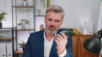Mature business man working, having mobile phone talk at office workplace using messenger chat apps video