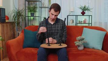 Man finishing assembling furniture at home in new apartment, successful table collect repair fixing video