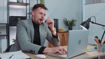 Bored sleepy business man worker working on laptop computer, yawning, falling asleep at office video