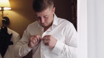 Stylish man in jacket fastens buttons, buttoning white shirt preparing to go out near window video