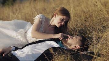 Newlyweds. Caucasian groom with bride lie on the grass on mountain slope video