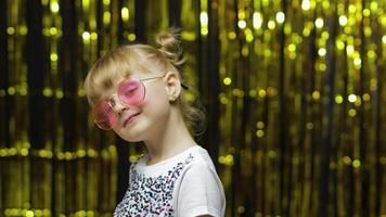 Child smiling, looking at camera, making fly kiss. Girl posing on background with foil curtain video