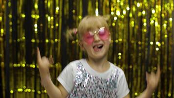 Child dancing waving hands fooling around. Girl 4-5 years old posing on background with foil curtain video