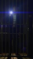 A Mysterious Figure is Seen Behind Bars, Holding a Flashlight in a Dark and Gloomy Cell video