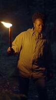 A person is holding a bright torch while exploring a dark and mysterious forest landscape video